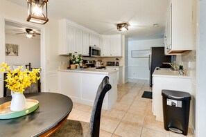 A modern kitchen with white cabinets, a central island, and a dining area with a table and chairs.
