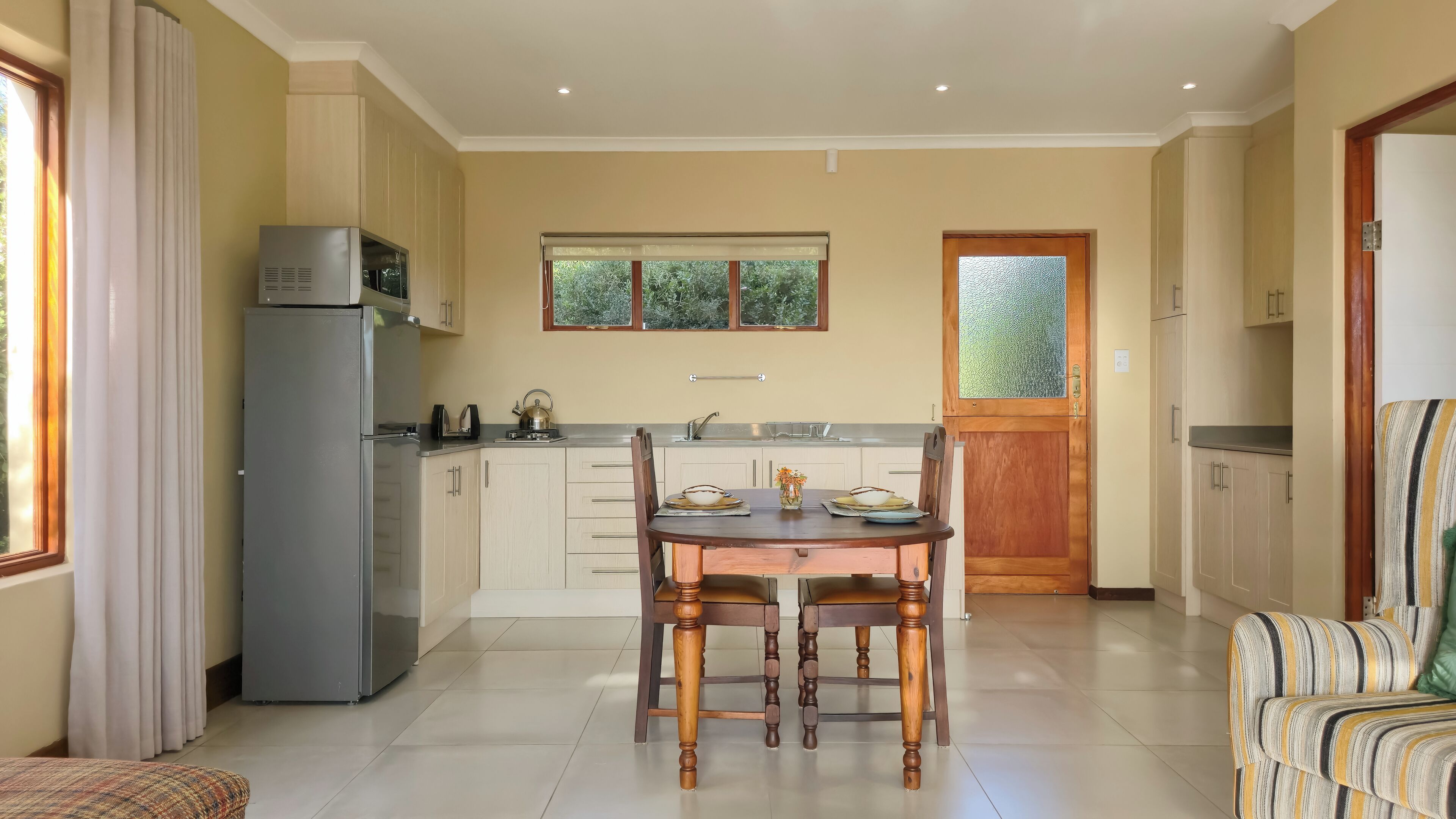 A compact kitchen with a dining table, chairs, and a refrigerator.