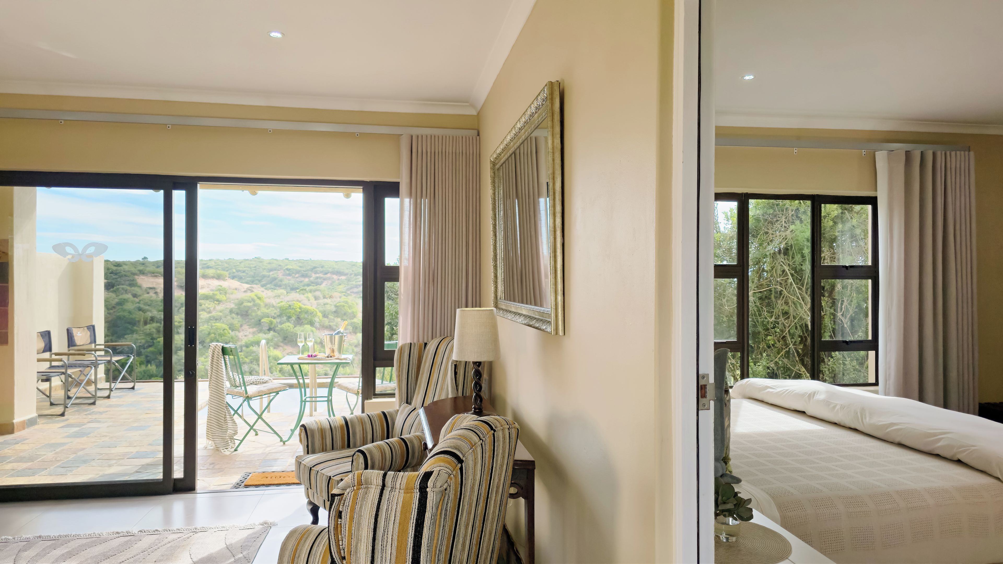 Ein Hotelzimmer mit Bett, einer Sitzecke mit Tisch und Stühlen und einem großen Fenster mit Blick ins Freie.