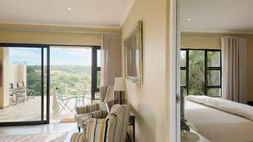 Ein Hotelzimmer mit Bett, einer Sitzecke mit Tisch und Stühlen und einem großen Fenster mit Blick ins Freie.
