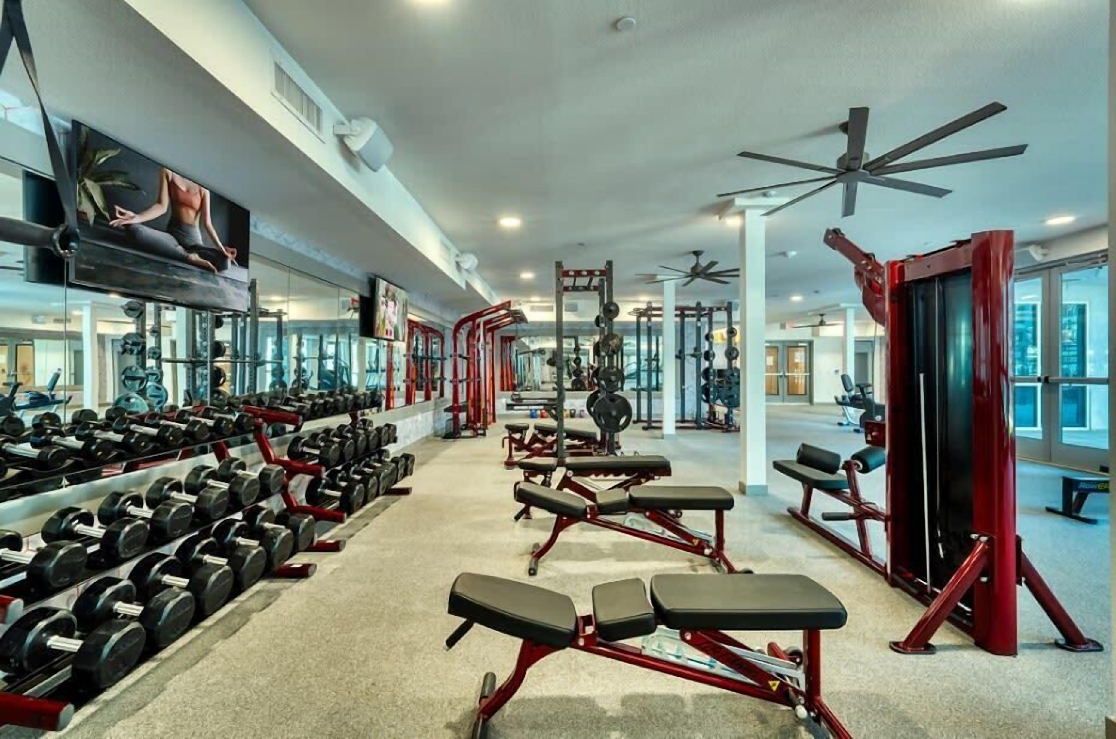 A gym with rows of dumbbells, benches, and weight machines.