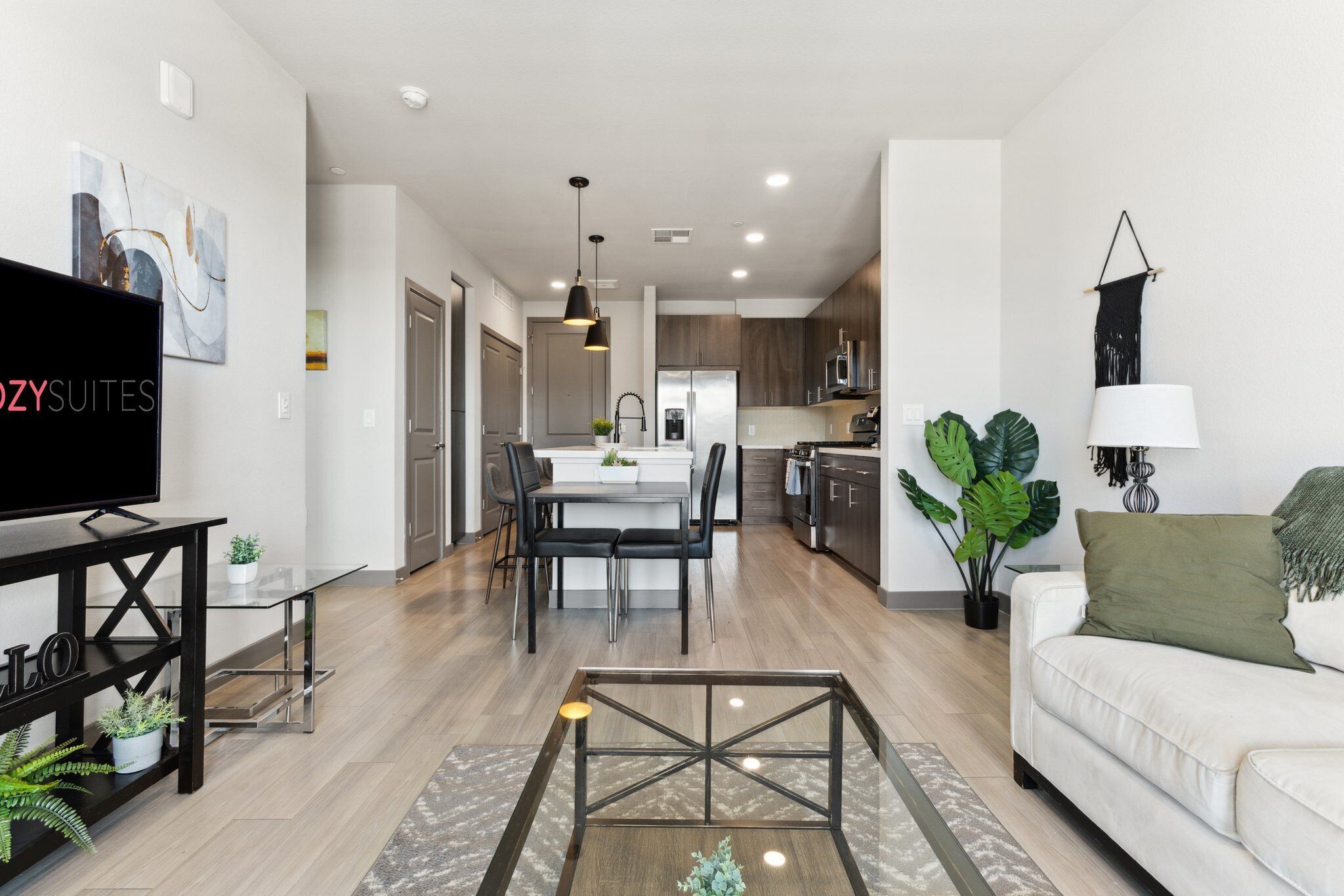 A modern living room with a flat-screen TV, a glass coffee table, and a white sofa.