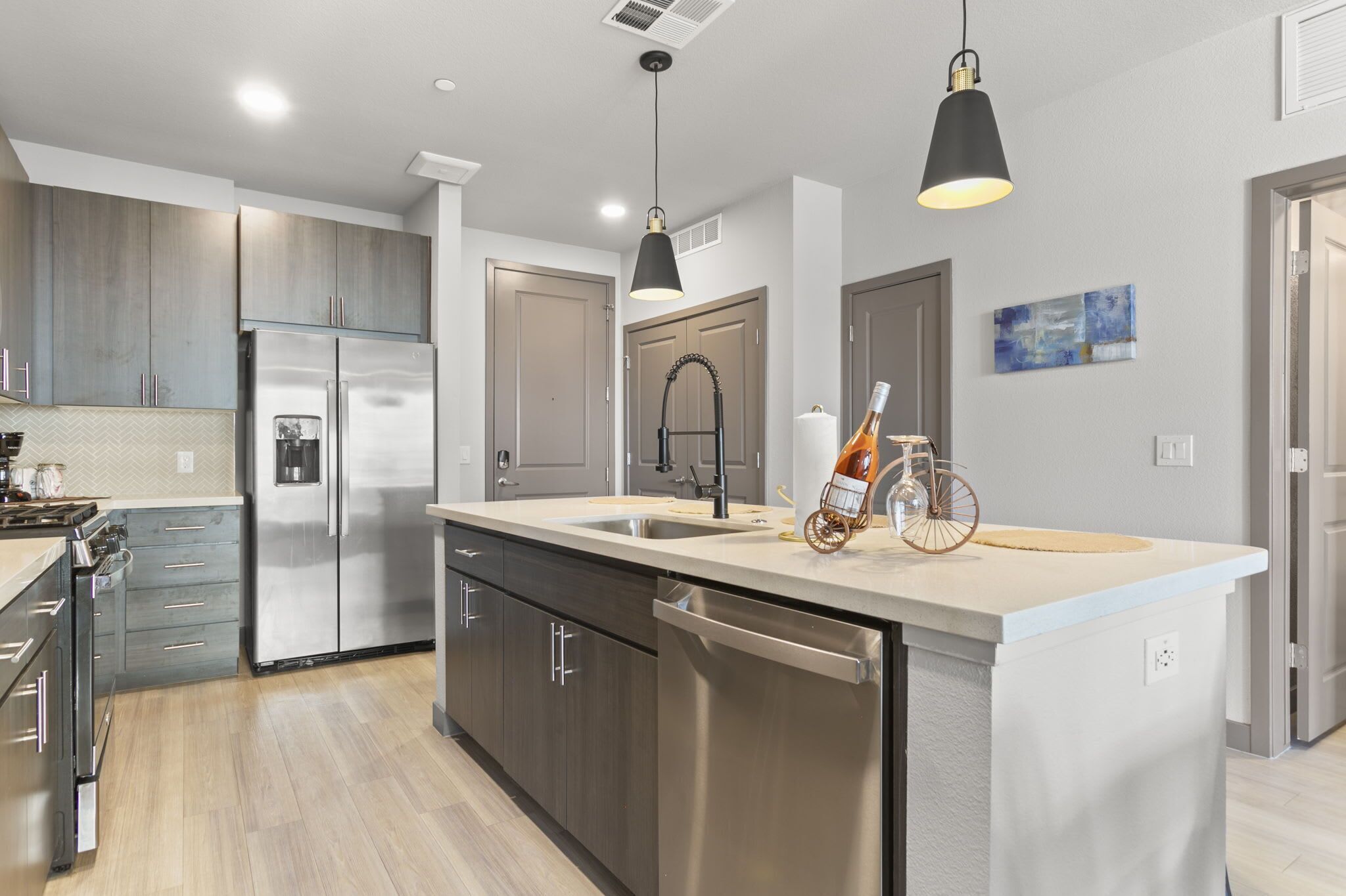 A modern kitchen with stainless steel appliances, a large island, and pendant lighting.