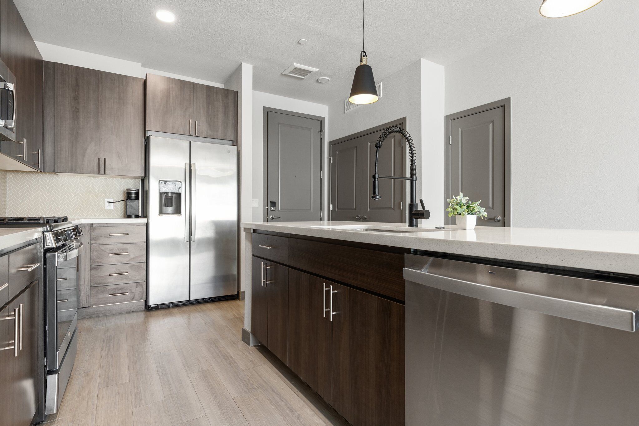 A modern kitchen with dark wood cabinets, stainless steel appliances, and a large island with a sink.