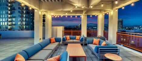 A rooftop lounge with a long sofa, smaller seating, and a coffee table.