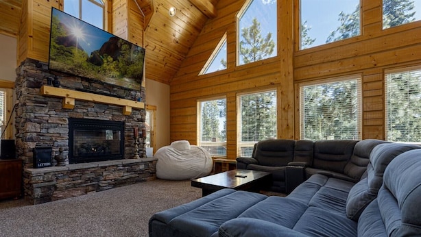 A cozy living room with a stone fireplace, a large sectional sofa, and a bean bag chair. - Browning Lodge Retreat! (Duck Creek Village)