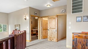 A spacious hallway with wooden doors, a carpeted floor, and a staircase with a wooden handrail. - PET-FRIENDLY FOREST RETREAT CABIN | HOT TUB, FIRE-PIT, & A/C (Duck Creek Village)