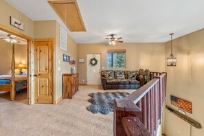 A spacious living area with a high ceiling, a wooden staircase, a leather sofa, and a rug. - PET-FRIENDLY FOREST RETREAT CABIN | HOT TUB, FIRE-PIT, & A/C (Duck Creek Village)