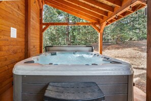 A hot tub under a wooden pergola with a view of a forest. - PET-FRIENDLY FOREST RETREAT CABIN | HOT TUB, FIRE-PIT, & A/C (Duck Creek Village)