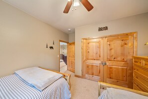 A bedroom with two beds, wooden wardrobe, and a ceiling fan. - PET-FRIENDLY FOREST RETREAT CABIN | HOT TUB, FIRE-PIT, & A/C (Duck Creek Village)