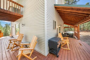 A wooden deck with two rocking chairs and a grill, overlooking a forested area. - PET-FRIENDLY FOREST RETREAT CABIN | HOT TUB, FIRE-PIT, & A/C (Duck Creek Village)