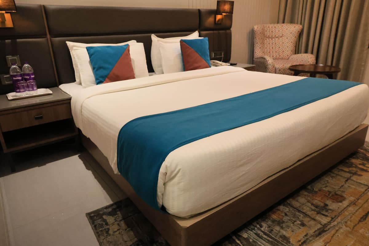 Une chambre d’hôtel avec un grand lit, une table de chevet avec une lampe, une chaise et une petite table.