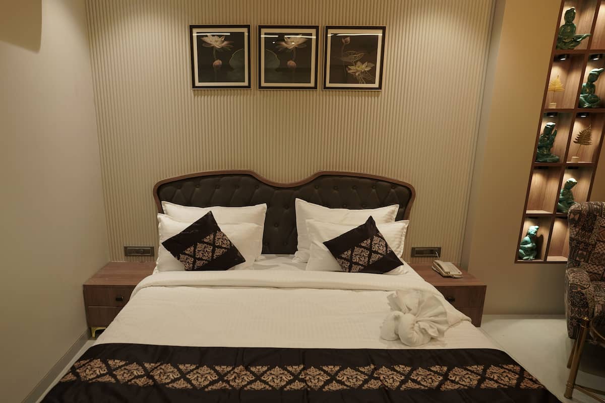 Un lit bien fait, recouvert d’une couvre-lit à motifs, avec une tête de lit à motifs capitonnés et une table de chevet sur laquelle se trouvent un téléphone et un petit objet décoratif.