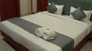 A hotel room with a large bed, a ceiling fan, and a wooden door. - Hotel Vijay Villas (Udaipur)