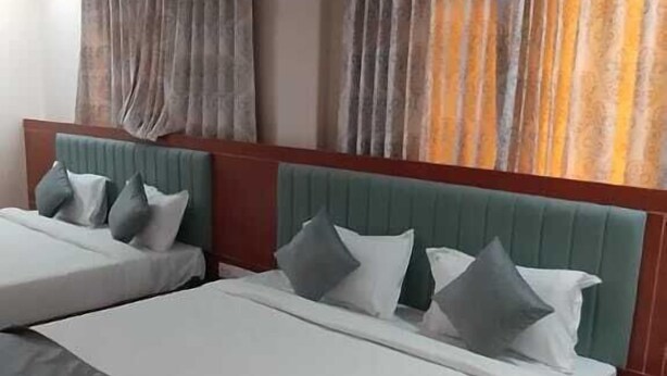 A hotel room with a large bed, two pillows, a ceiling fan, and curtains. - Hotel Vijay Villas (Udaipur)