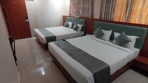 A hotel room with two beds, a wooden headboard, and a small bedside table. - Hotel Vijay Villas (Udaipur)