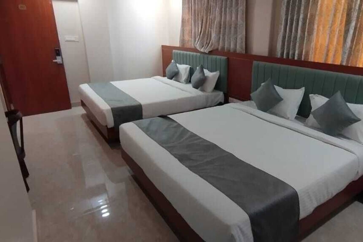 A hotel room with two beds, a wooden headboard, and a small bedside table.