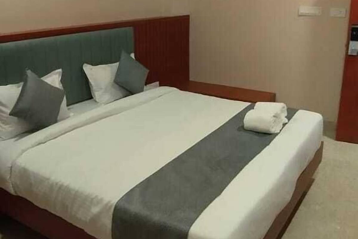 A hotel room with a large bed, a wooden headboard, and a ceiling fan.