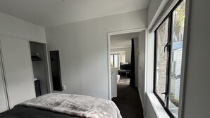 Un dormitorio con cama, armario, espejo y ventana con vistas al exterior.