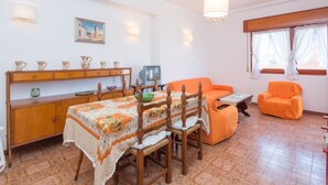 A cozy living room with a dining table, chairs, a sofa, and a TV. - Cosy apartment for 4 guests with WIFI, TV and terrace (Torvaianica)