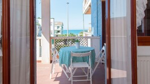 A balcony with a table and chairs, a view of the sea, and buildings in the background. - Cosy apartment for 4 guests with WIFI, TV and terrace (Torvaianica)