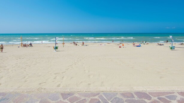 A beach with clear skies, a sandy shore, and a few people and umbrellas. - Cosy apartment for 4 guests with WIFI, TV and terrace (Torvaianica)