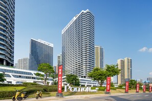 Stunning high-rise building with a wavy facade, surrounded by lush greenery and a well-manicured lawn.