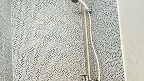 Ducha con pared de mosaico de azulejos y cabezal de ducha de mano.