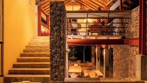 A multi-level stone building with a wooden staircase leading to a lower level. - The River House Dambulla by The Serendipity Collection (Dambulla)