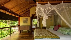 A bedroom with a canopy bed, wooden flooring, and a view of greenery outside. - The River House Dambulla by The Serendipity Collection (Dambulla)