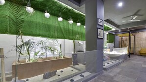Um hall moderno com parede verde, plantas em vasos, espaço para sentar e exposição náutica.