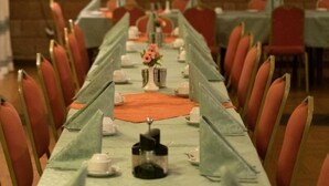 A long dining table with chairs, set with white plates, cups, and a centerpiece. - Rock Land Guest House (Lalibela)