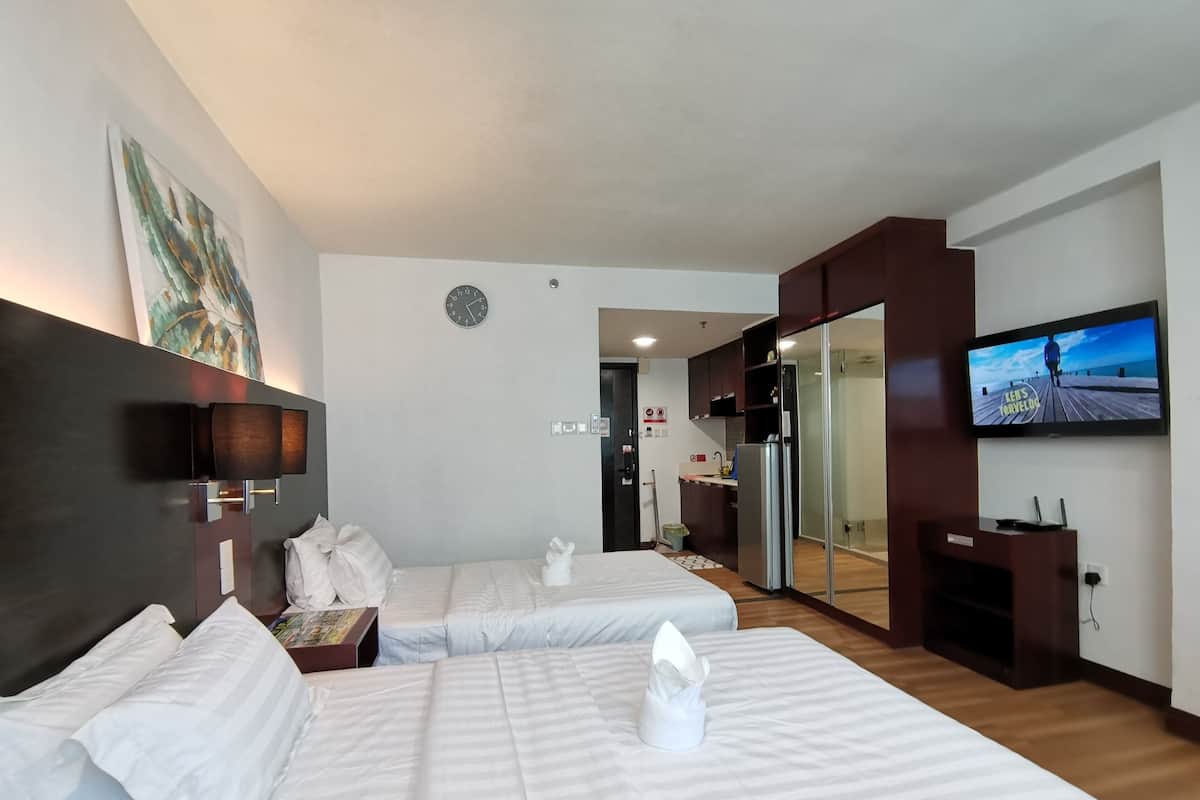 A hotel room with two beds, a TV, a painting, and a clock.
