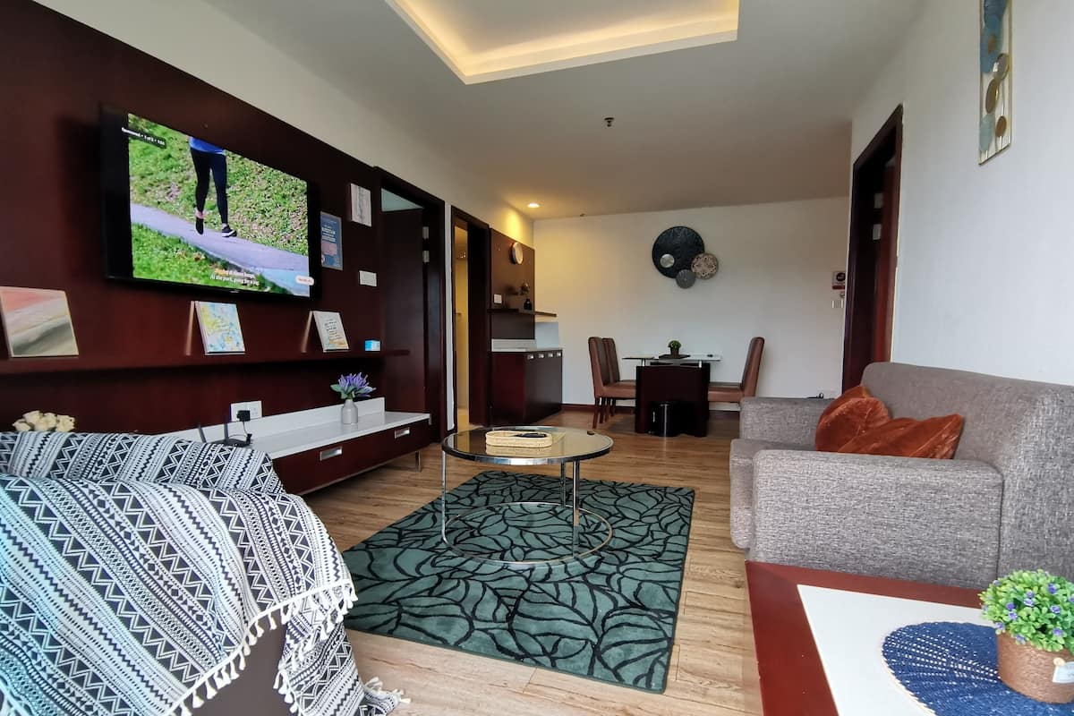 A modern living room with a sofa, a coffee table, and a TV mounted on the wall.