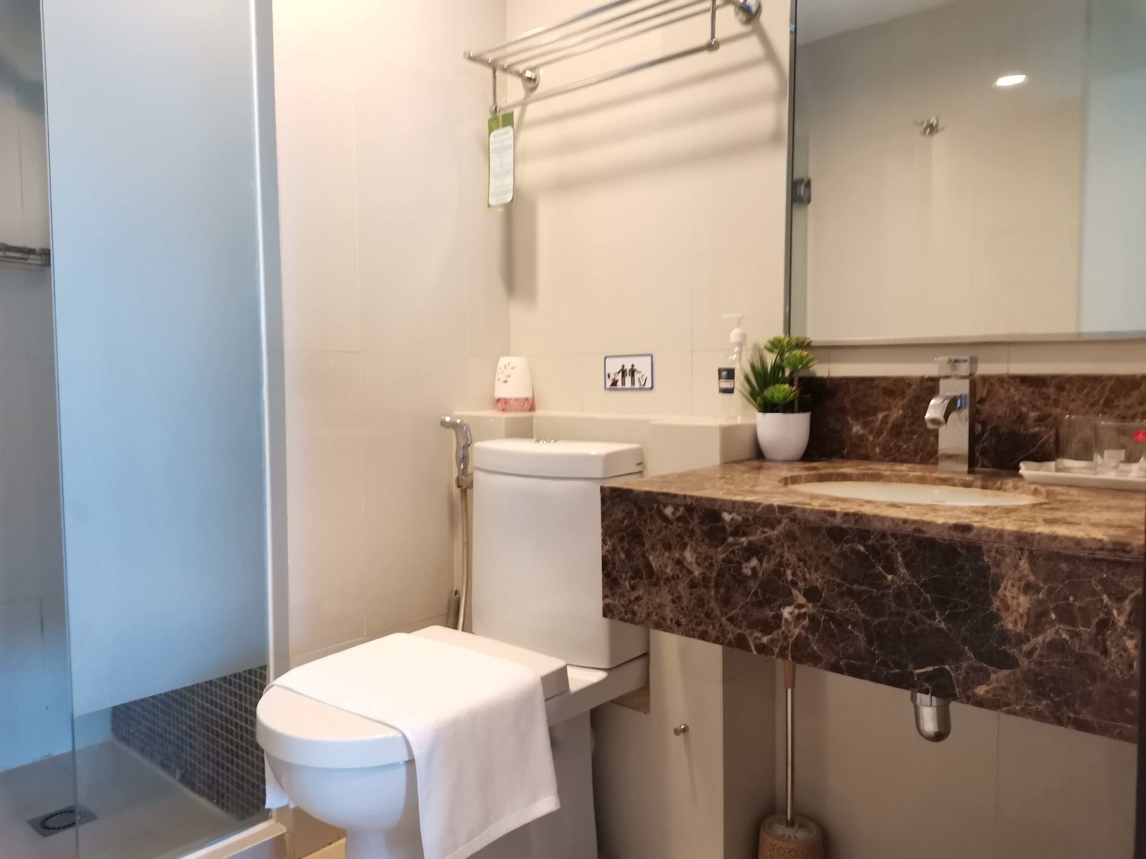 Um banheiro moderno com bancada de mármore, vaso sanitário, chuveiro e pia.