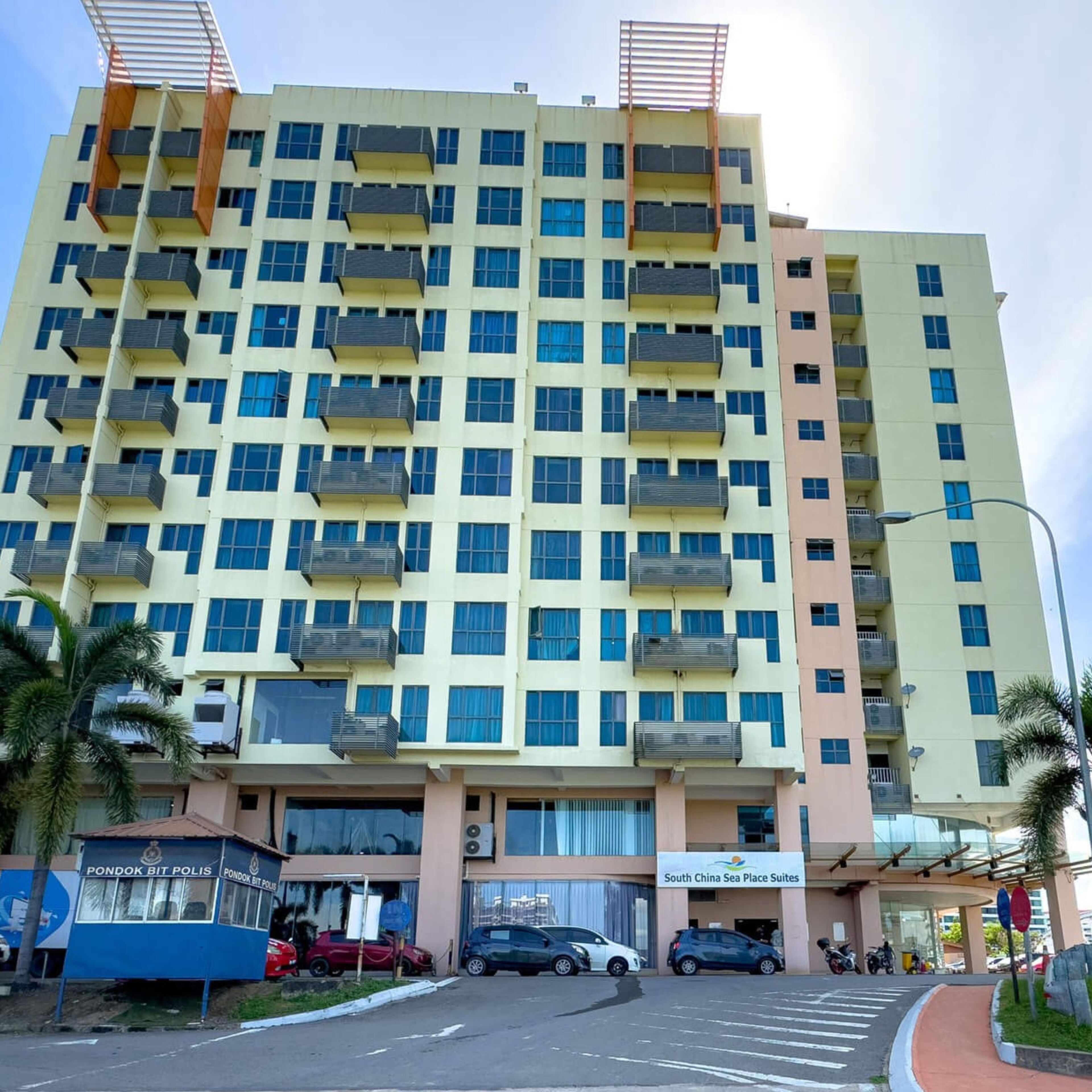 Un hôtel à plusieurs étages doté de balcons, un poste de police et une vue sur la mer.