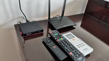Et bord med en sort LongTV-boks, en sort router og to fjernbetjeninger.