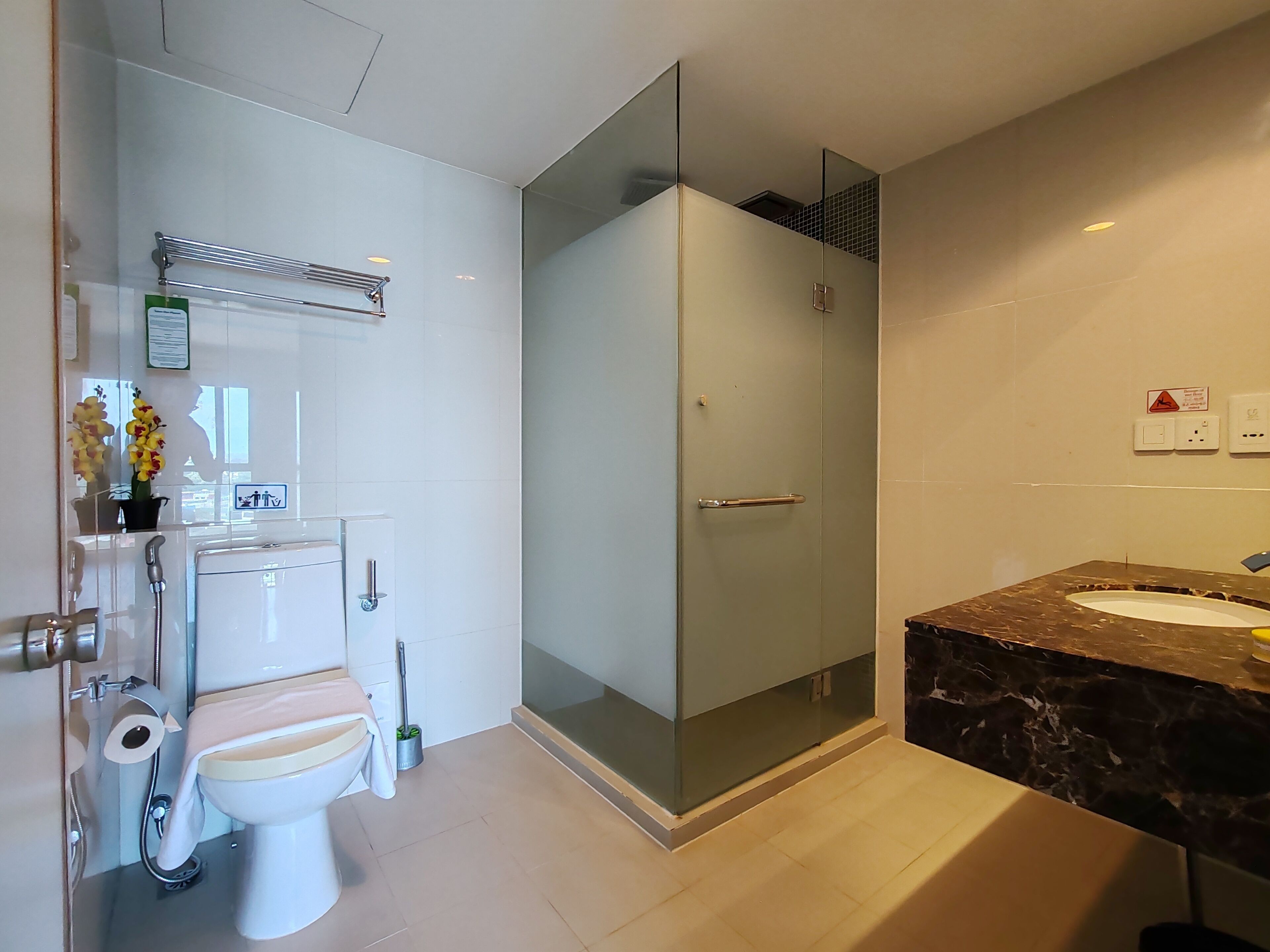 A modern bathroom with a glass-enclosed shower, a toilet, and a sink with a marble countertop.