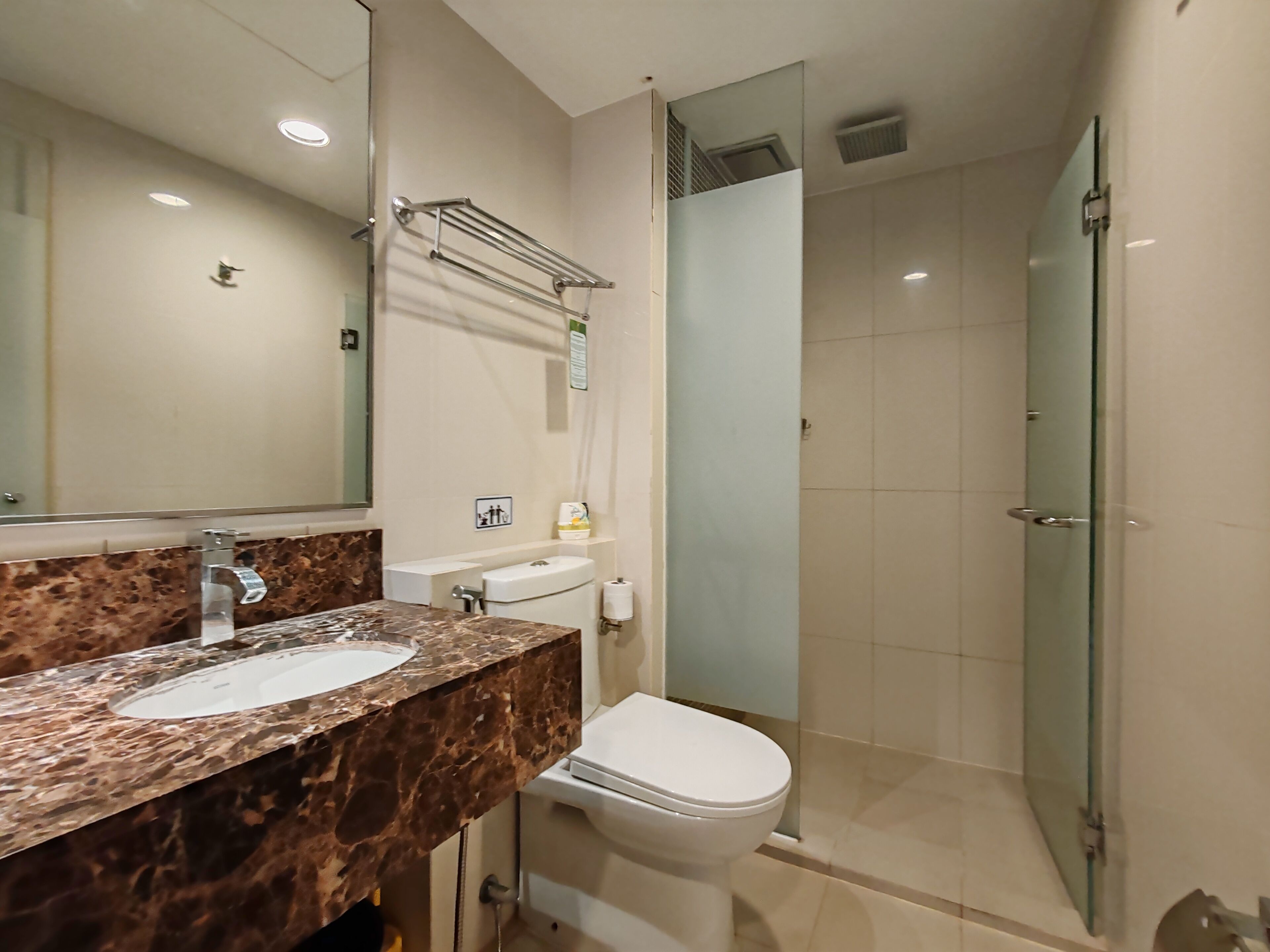 A bathroom with a marble sink, a toilet, and a glass shower enclosure.