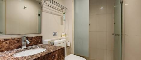 A bathroom with a marble sink, a toilet, and a glass shower enclosure.