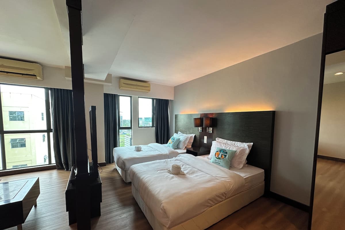 A hotel room with two beds, a TV, and a large window with curtains.