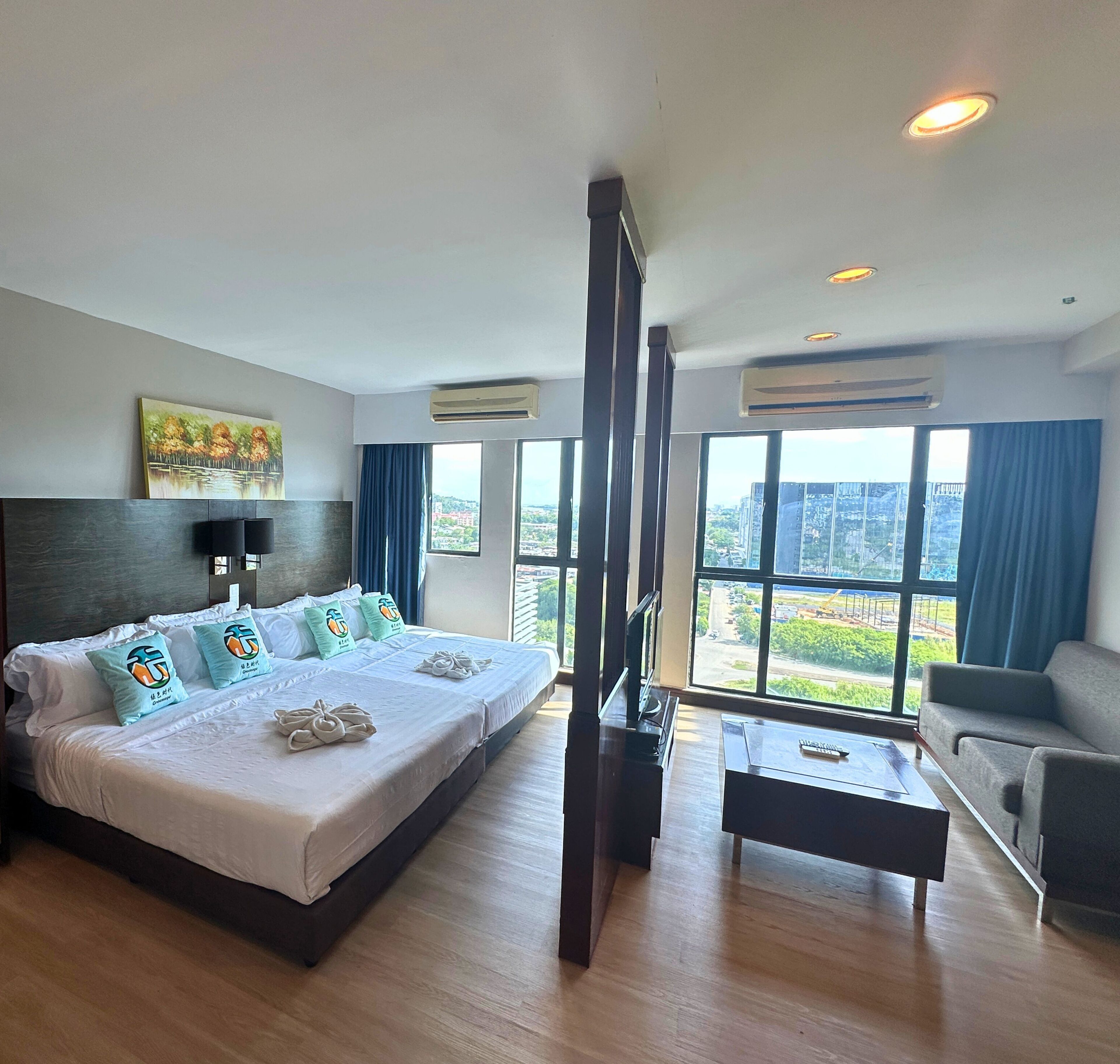 Une chambre d’hôtel avec un grand lit, une télévision, un canapé et une vue sur la ville.
