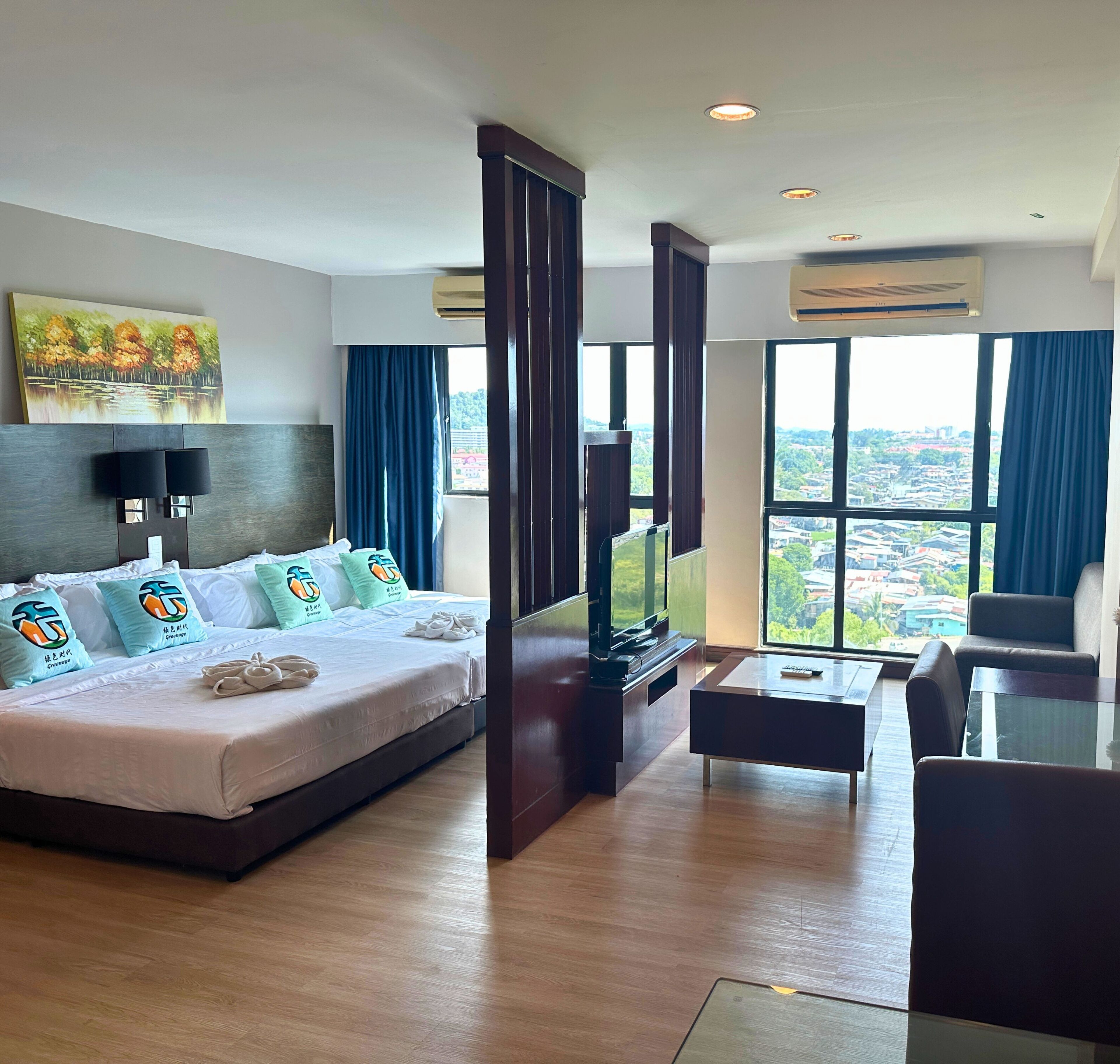 A hotel room with a large bed, a TV, a desk, and a view of the city.