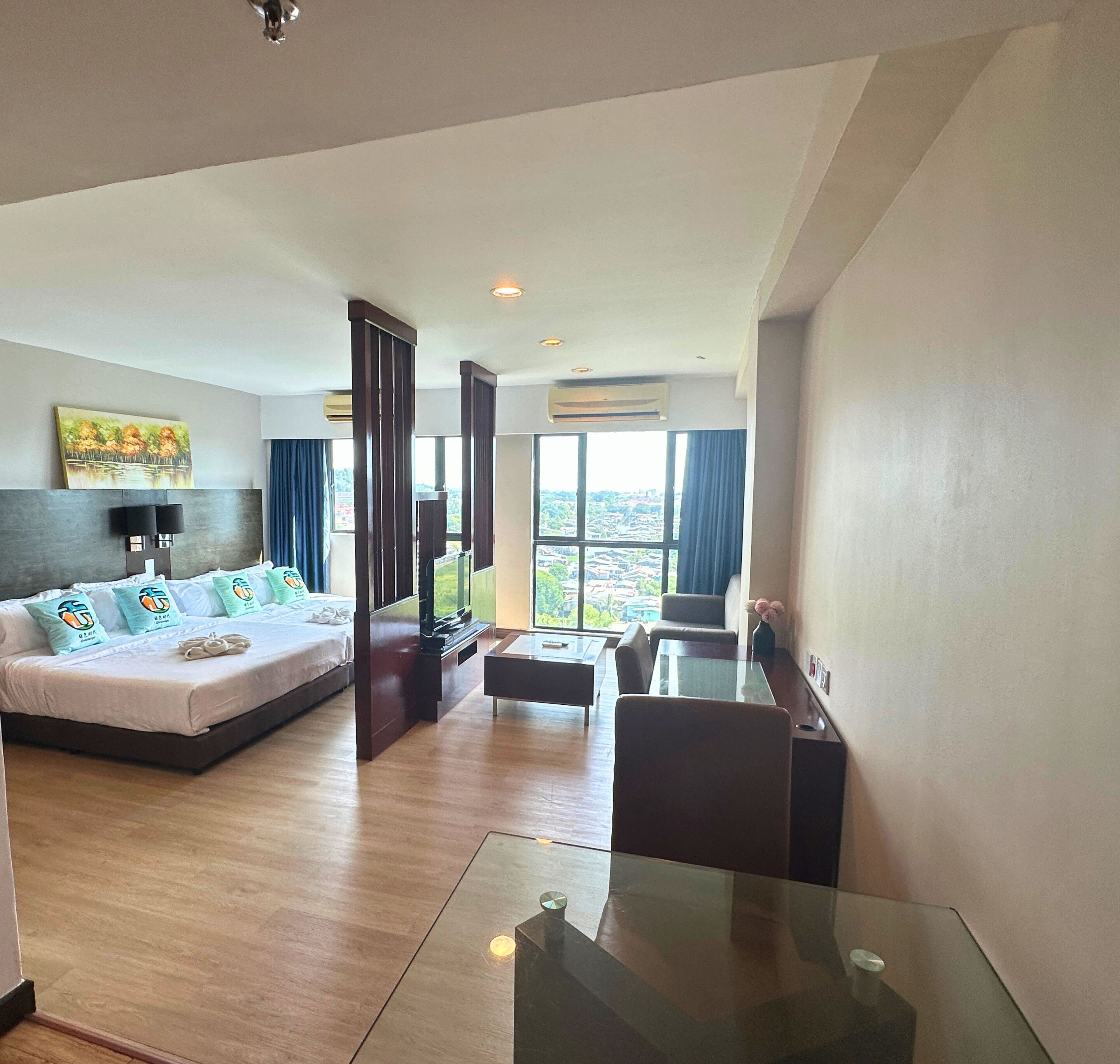 A hotel room with a bed, a TV, a desk, and a view of the city.