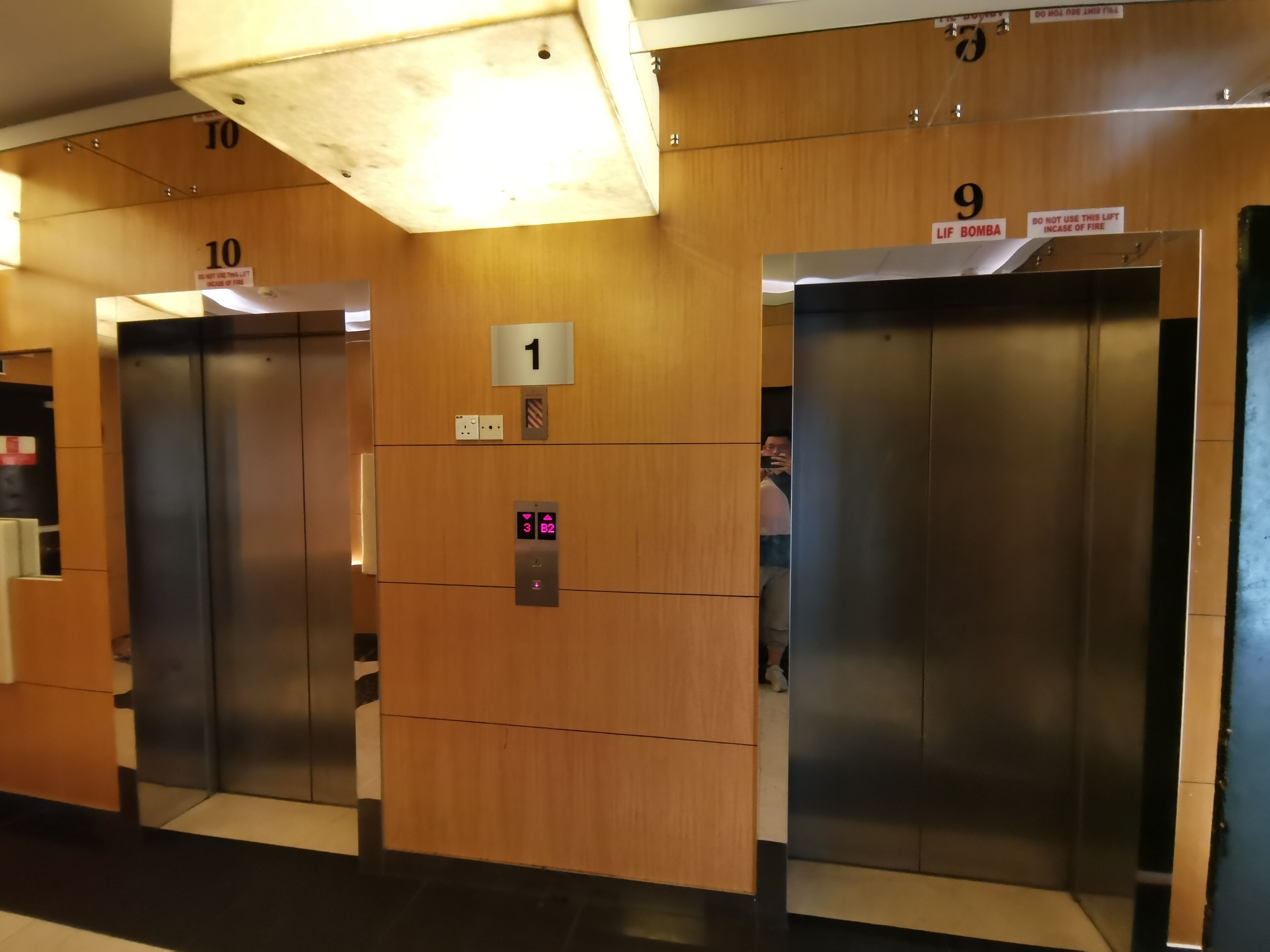 Una fila de ascensores con paneles de madera y letreros numerados encima de cada uno.