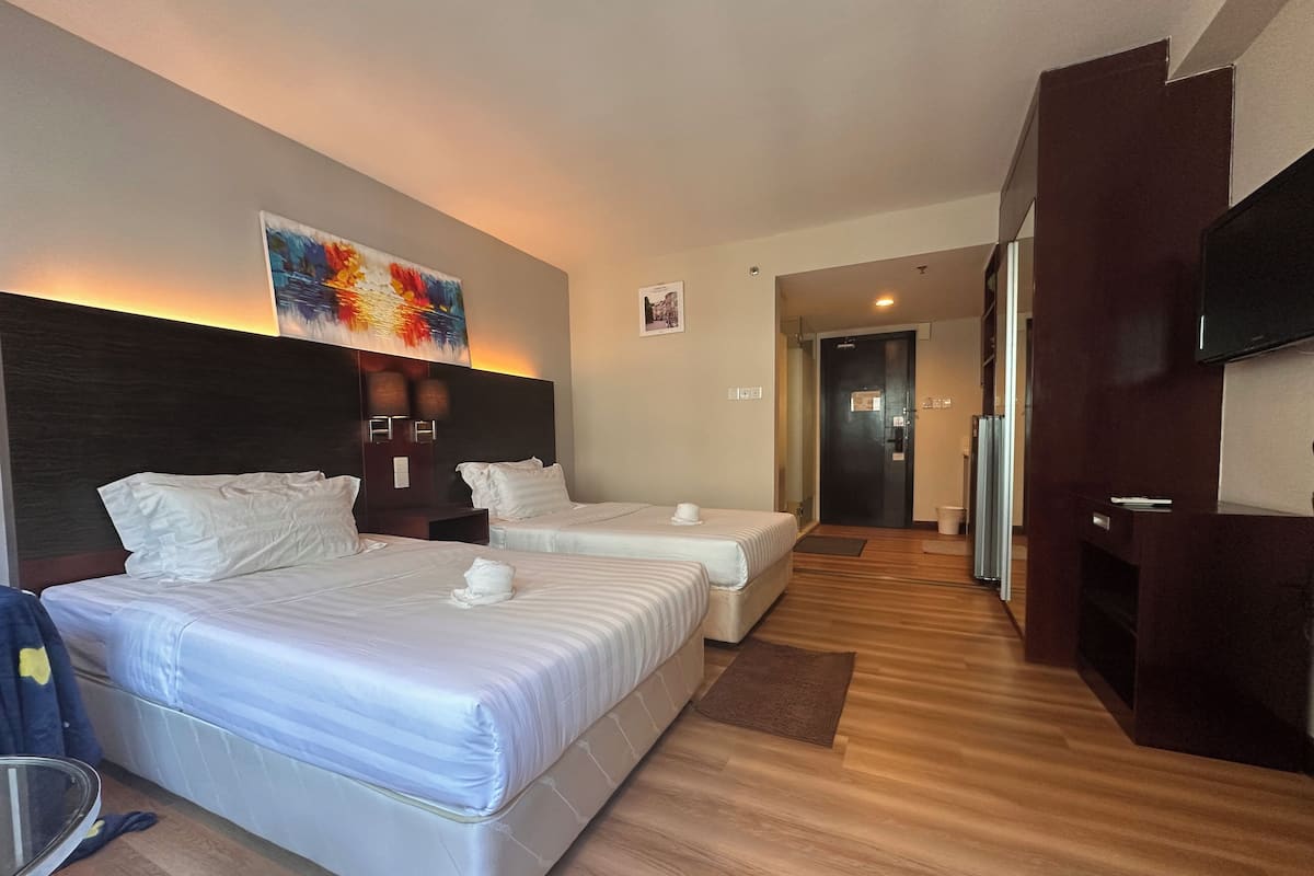 A hotel room with two beds, a flat-screen TV, and a painting on the wall.