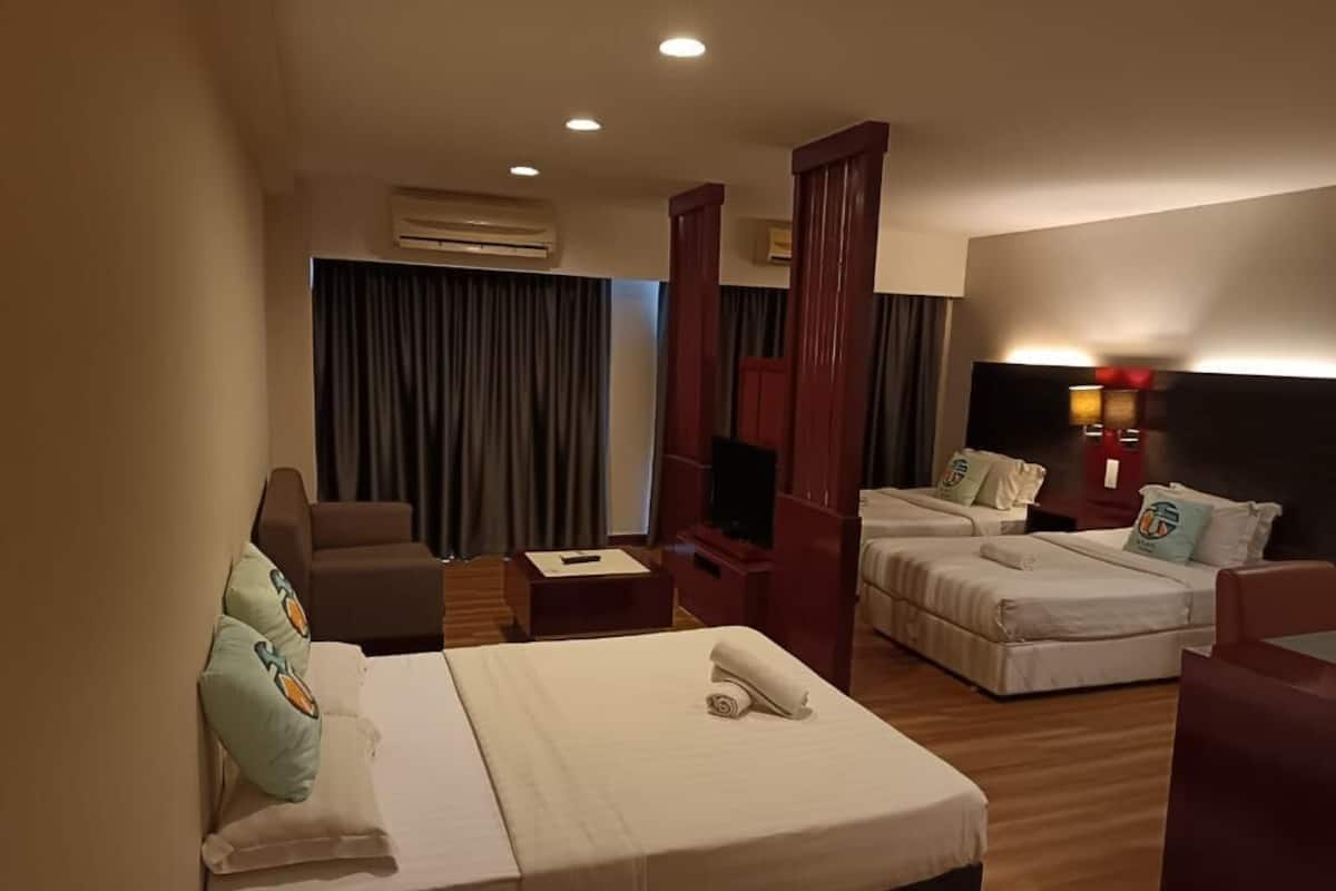 A hotel room with two beds, a sofa, a TV, and a desk.
