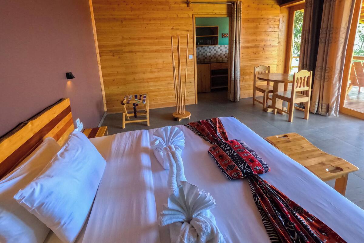 A wooden cabin room with a bed, a small table, and a chair.