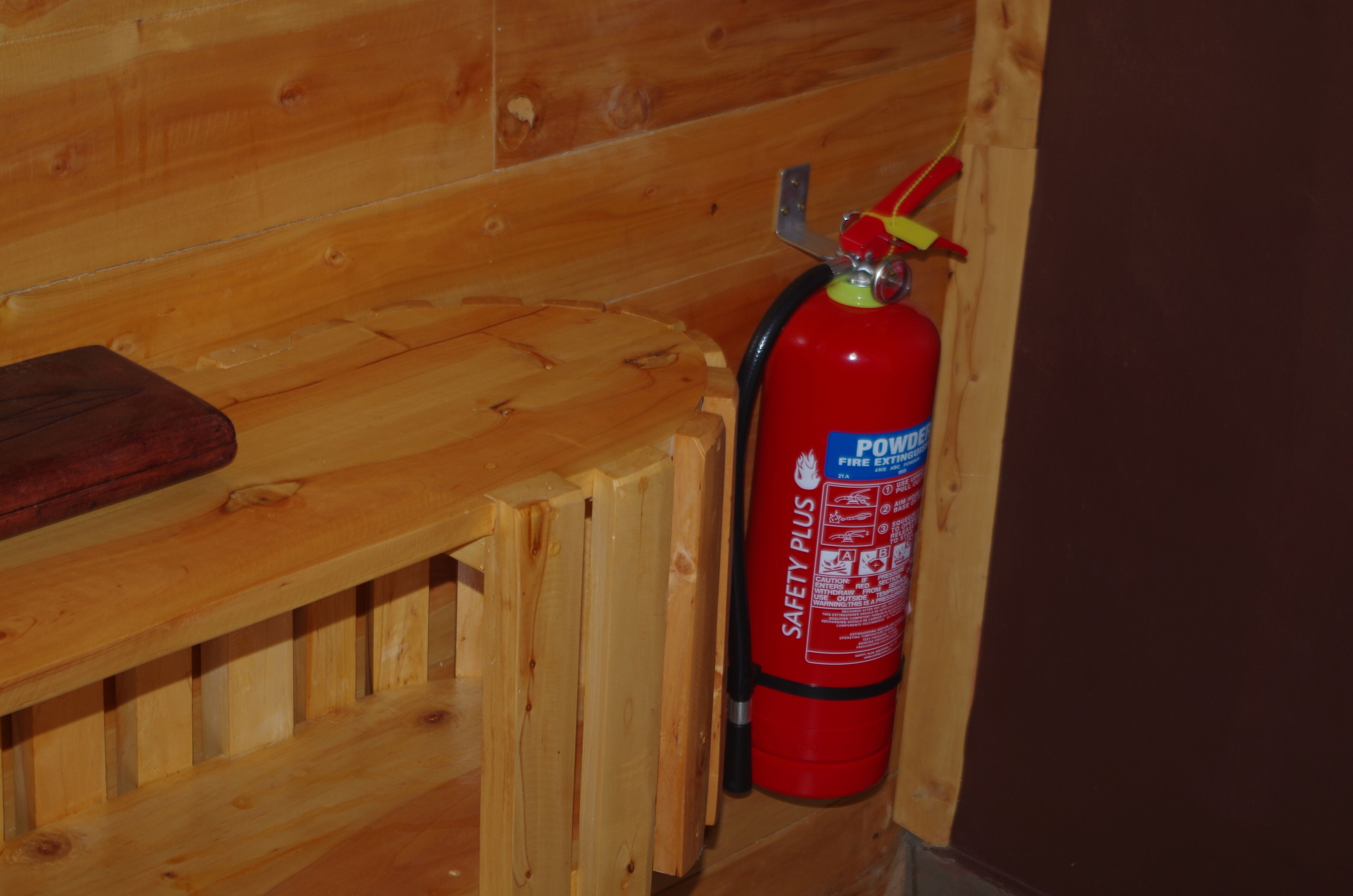 A wooden wall with a red fire extinguisher mounted on it.