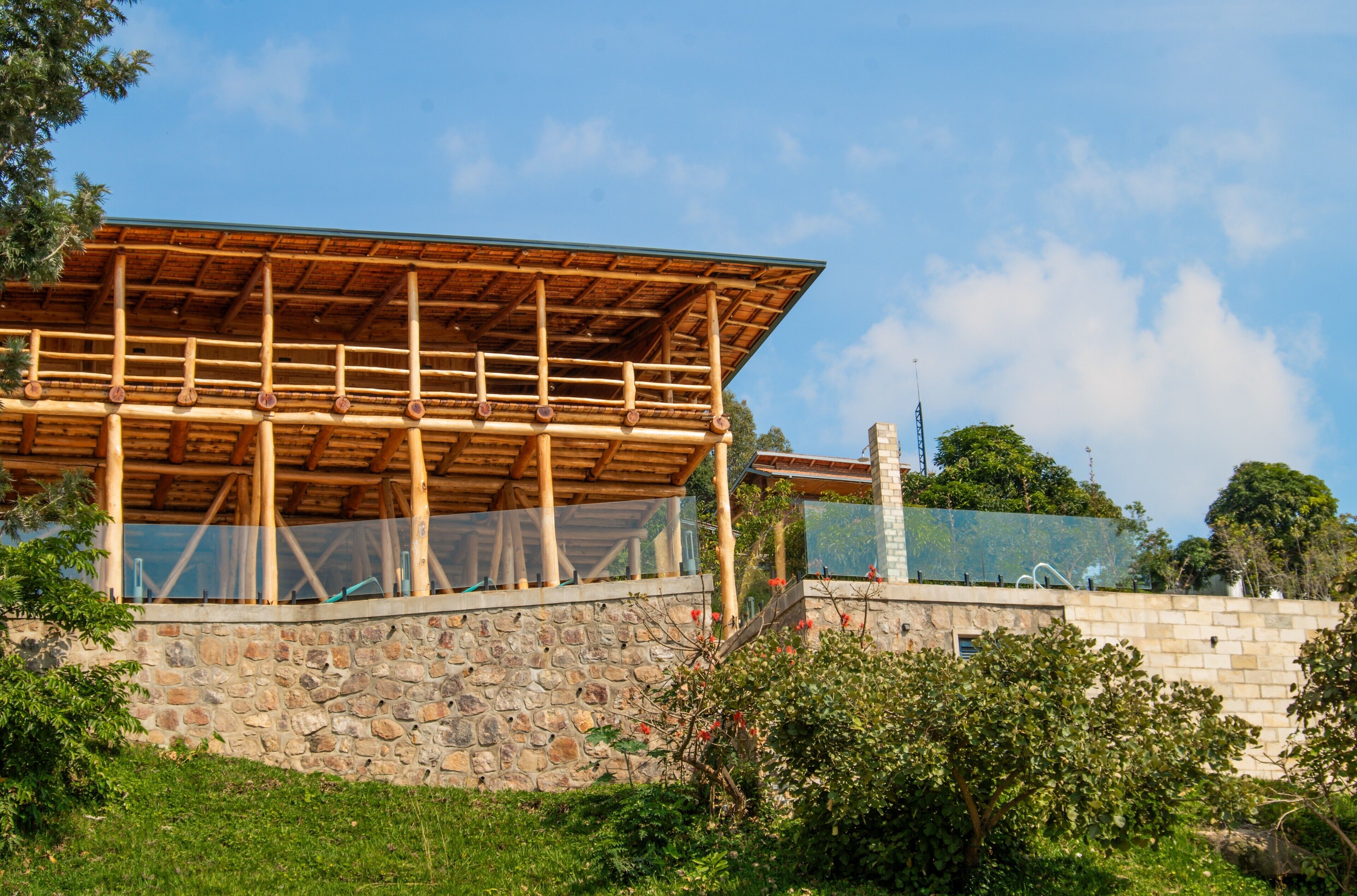A building with a wooden structure and stone walls, surrounded by greenery.